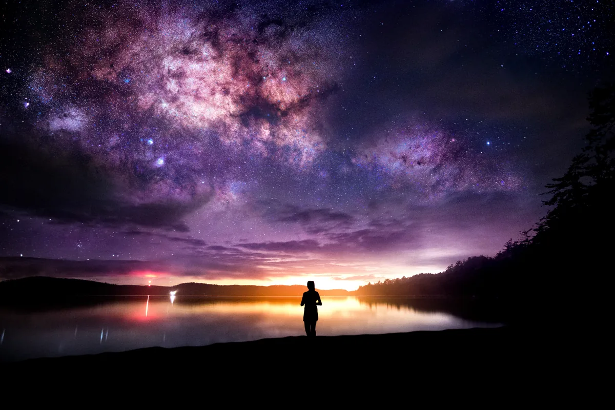 A composite of the Milky Way over a lake in Dwight, Ontario, with a figure standing on the shore