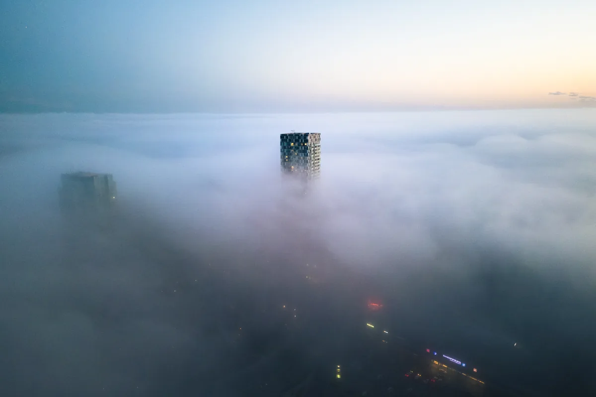 An aerial view of a single tower rising out of a sea of fog over Etobicoke, Toronto