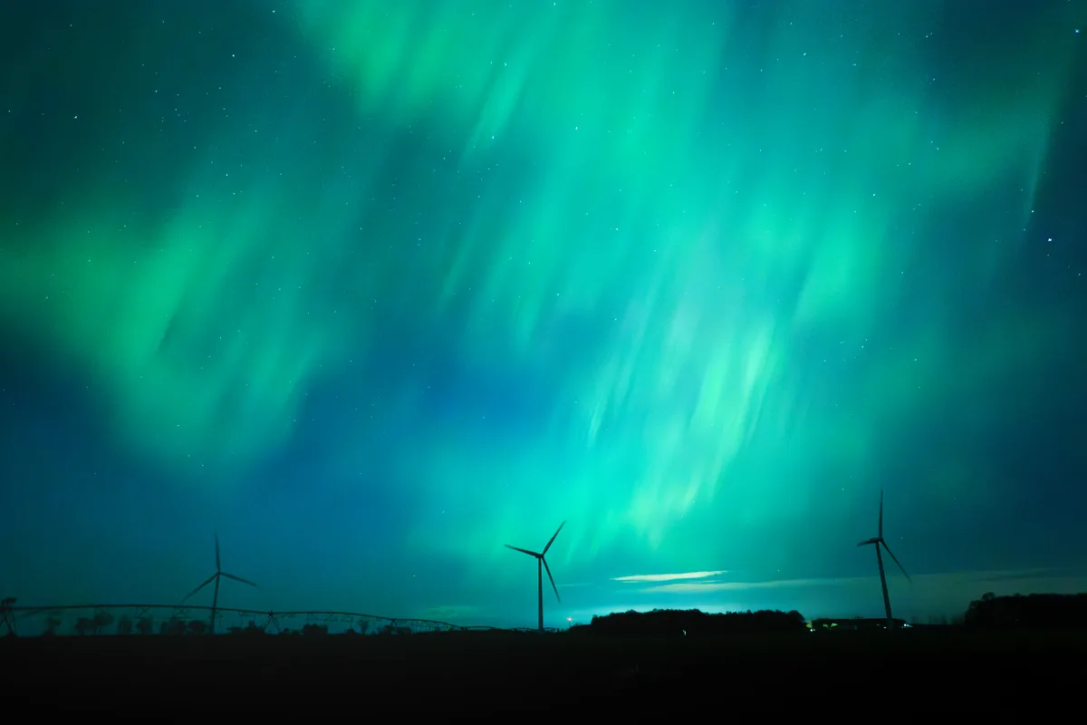 Green northern lights dancing over wind turbines in Grey County, Ontario