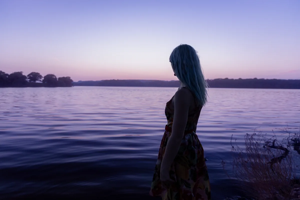 A woman in silhouette beside the water at dusk in Hamilton, Ontario
