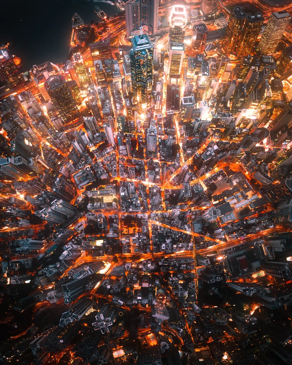 An aerial panorama looking straight down on the glowing orange streets of Hong Kong at night