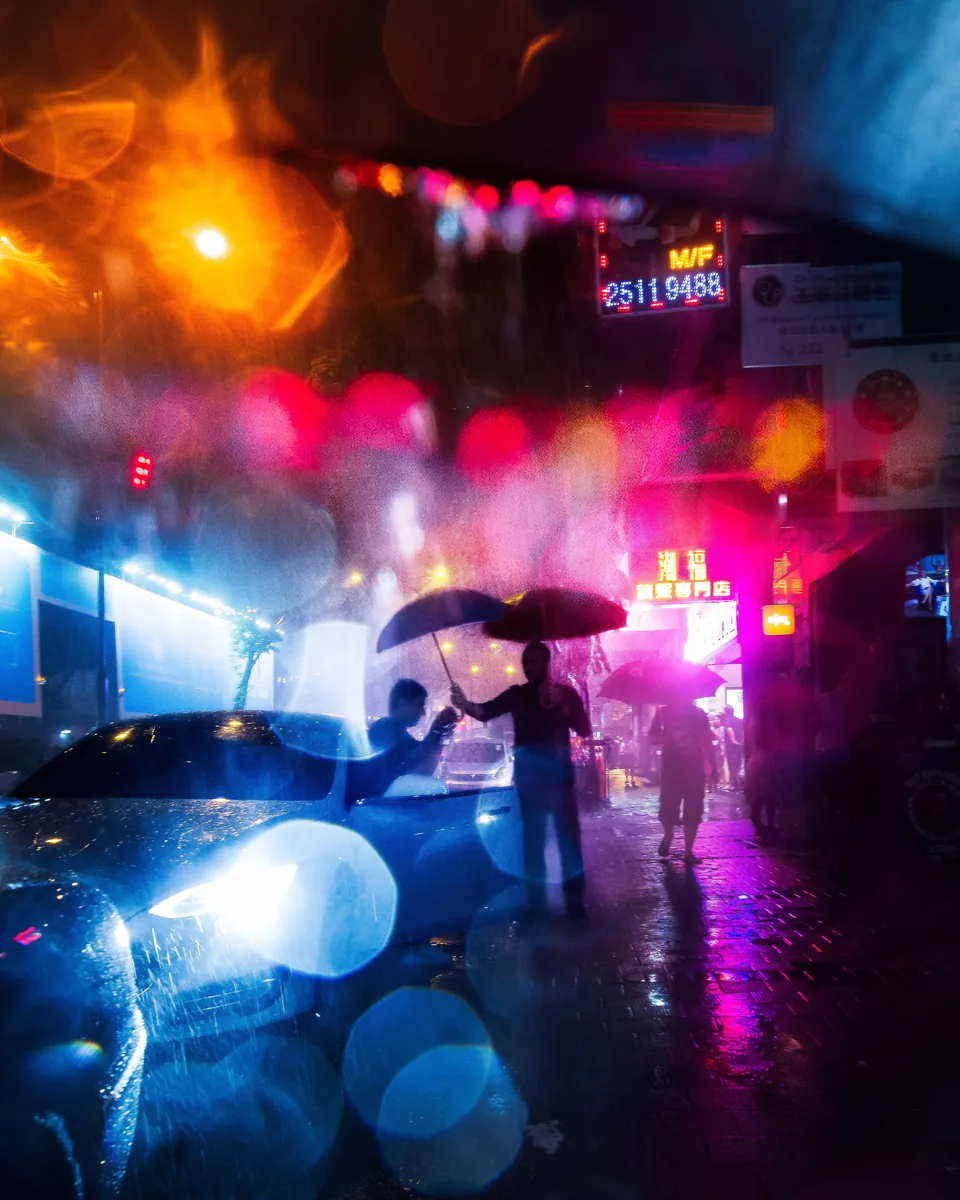 Neon Rain, people with umbrellas under blurred neon light on a rainy night in Wan Chai, Hong Kong