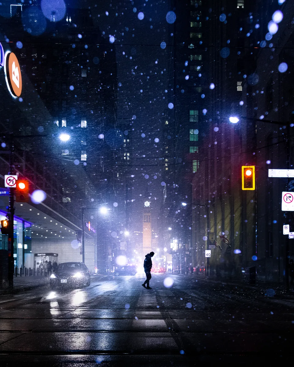 A snowstorm at night in Toronto's Financial District, traffic lights glowing through the falling snow