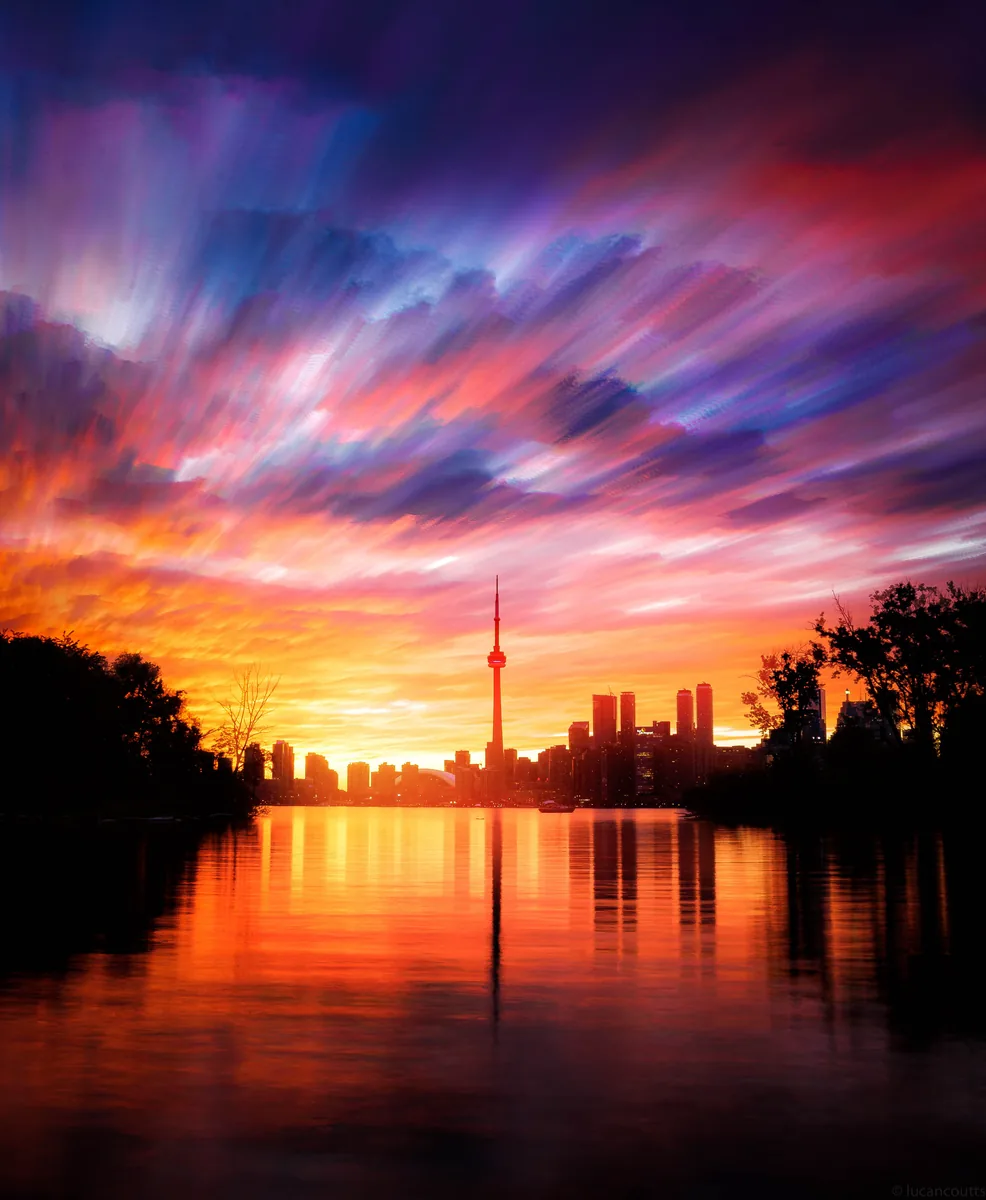 Long exposure of a fiery sunset over the Toronto skyline and CN Tower, reflected in the water off the Toronto Islands