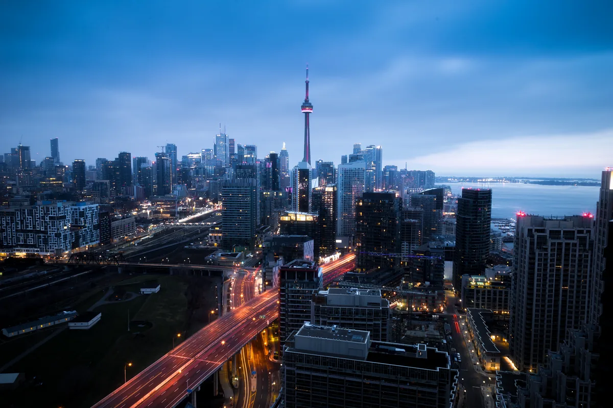 The Toronto skyline and CN Tower at blue hour, with the Gardiner Expressway and Lake Ontario beyond