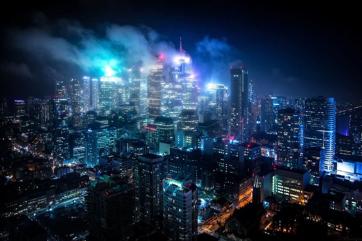 Downtown Toronto towers glowing under low, lit-up clouds at night